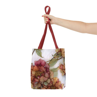 Vintage Peony Tote Bag with watercolor peony bloom design and red handles held by hand against white background