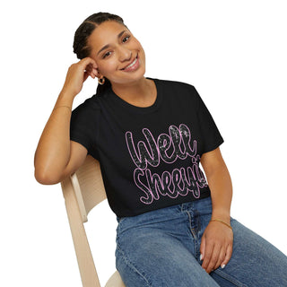 Woman wearing black casual statement tee with "Well Sheeyit!" text sitting on chair