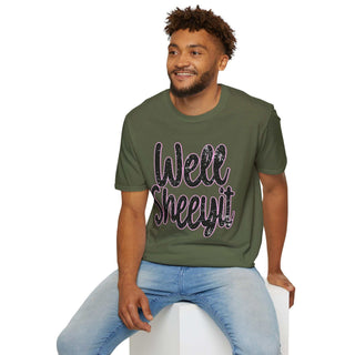 Man wearing olive green casual statement tee with "Well Sheeyit!" text design sitting on white block