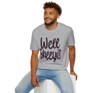 Man wearing gray casual statement tee with "Well Sheeyit!" text and blue jeans sitting on white block