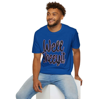 Man wearing blue casual statement tee with "Well Sheeyit!" text sitting on white block